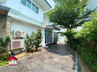 Exterior view of a two-story house with a garden and outdoor air conditioning units