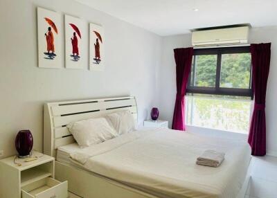 Bedroom with double bed, dresser, air conditioner, window with curtains