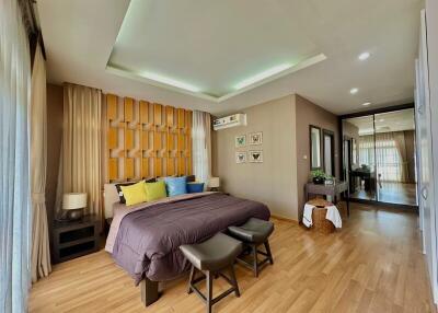 Spacious modern bedroom with large mirror and wooden floor