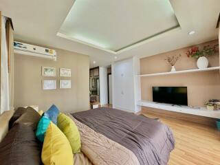 Modern bedroom with decorative pillows and large TV