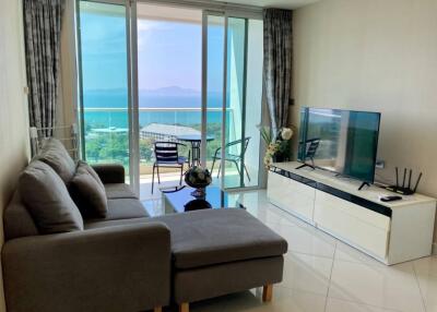 Modern living room with a sea view, featuring a couch, TV, and balcony access