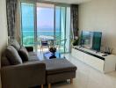 Modern living room with a sea view, featuring a couch, TV, and balcony access