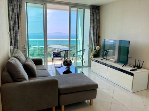 Modern living room with a sea view, featuring a couch, TV, and balcony access