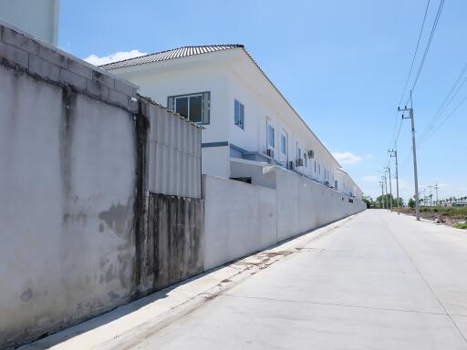 Exterior view of a residential building with a long boundary wall from the street