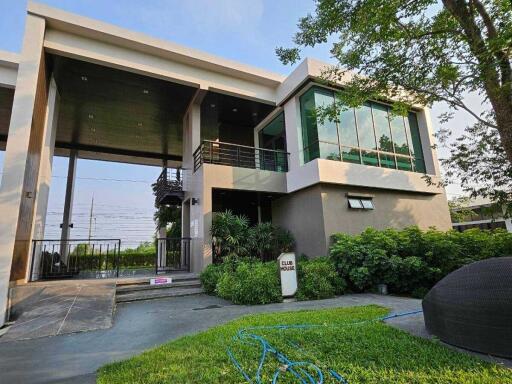 Modern two-story clubhouse with large windows and well-manicured garden