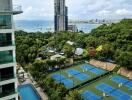 Scenic view of outdoor tennis courts, residential buildings, and city skyline