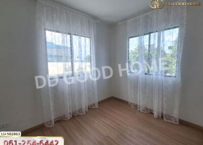 Bright, empty bedroom with wooden flooring and sheer curtains