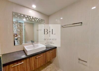 Modern bathroom with large mirror, sink, vanity, and towel rack.