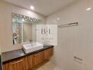 Modern bathroom with large mirror, sink, vanity, and towel rack.