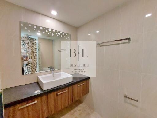 Modern bathroom with large mirror, sink, vanity, and towel rack.