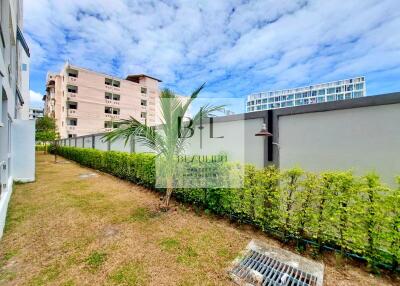 Outdoor area of the property with lawn, hedges, and surrounding buildings