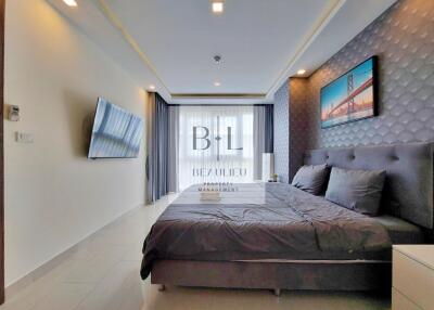 Modern, well-lit bedroom with a large bed and wall-mounted TV