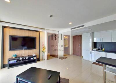 Modern living room with wall-mounted TV and adjacent kitchen area