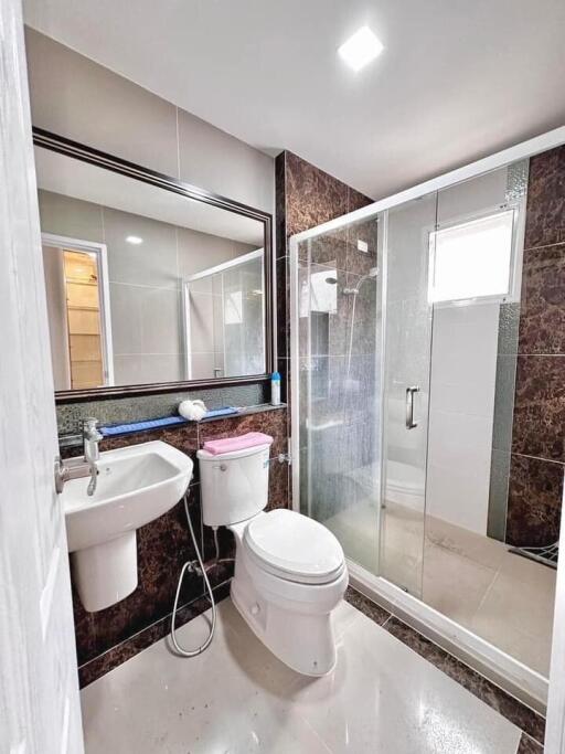 Modern bathroom with glass enclosed shower, large mirror and contemporary fixtures