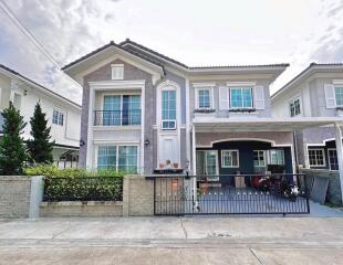 Exterior view of a two-story residential house with a front yard and driveway