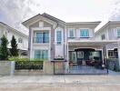 Exterior view of a two-story residential house with a front yard and driveway