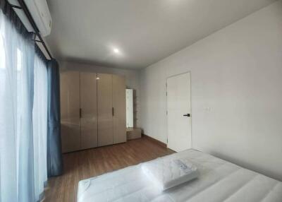 Modern bedroom with wooden flooring, bed, wardrobe, and large windows with blue curtains