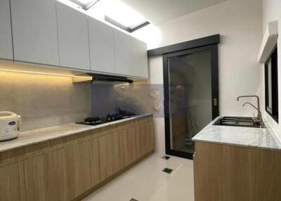 Modern kitchen with wood cabinets, gas stove, sink, and large window.