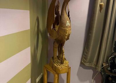 Decorative wooden crane statue on pedestal in corner of room