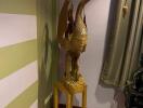 Decorative wooden crane statue on pedestal in corner of room