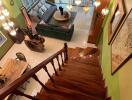 View of a well-lit main living area from the top of a wooden staircase