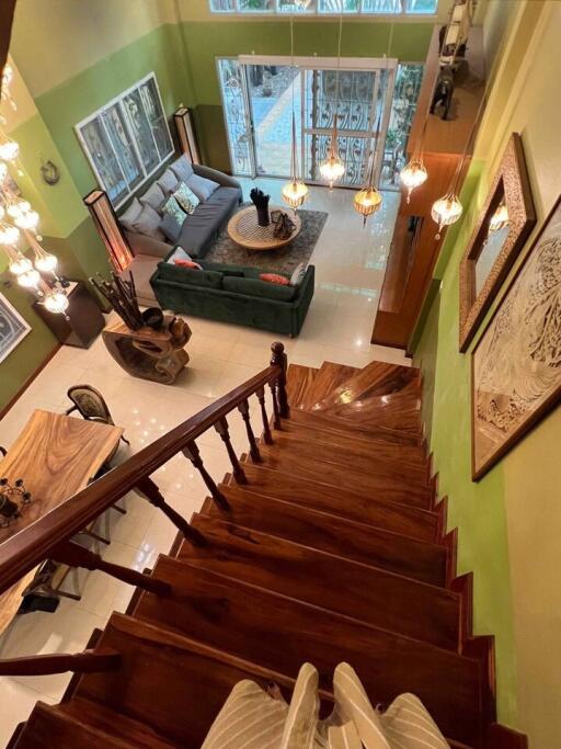 View of a well-lit main living area from the top of a wooden staircase