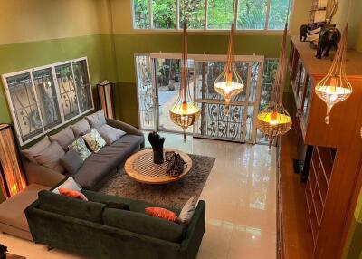 Spacious living room with a large gray sectional sofa and coffee table, featuring modern hanging lights and large windows offering plenty of natural light.