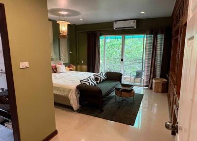 Spacious bedroom with large bed, cozy seating area, and glass doors leading to a view