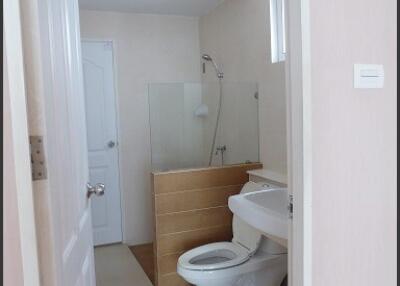 Bathroom with white door, toilet, sink, and shower area with glass partition