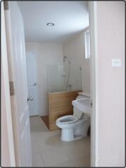 Bathroom with white door, toilet, sink, and shower area with glass partition