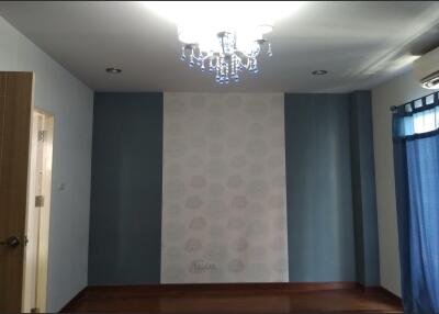 Empty bedroom with chandelier, blue accent walls, wooden flooring, and blue curtains