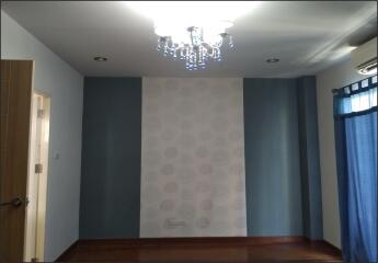 Empty bedroom with chandelier, blue accent walls, wooden flooring, and blue curtains