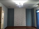 Empty bedroom with chandelier, blue accent walls, wooden flooring, and blue curtains