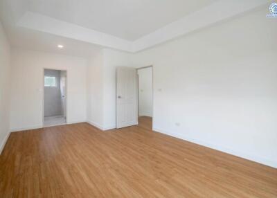 Spacious empty bedroom with wooden flooring and two doorways