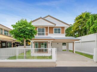 Exterior view of a modern two-story house with a white fence and driveway