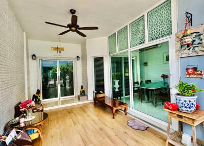 Cozy patio area with wooden benches, a glass table, potted plants, and an overhead fan