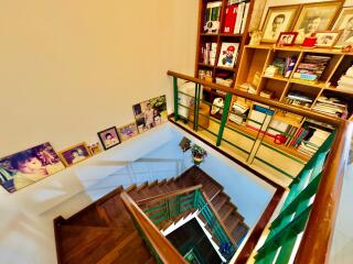 View of the staircase with wooden steps and handrails, adorned with pictures and a bookshelf