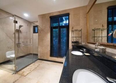 Modern bathroom with glass shower, double sinks, and marble flooring