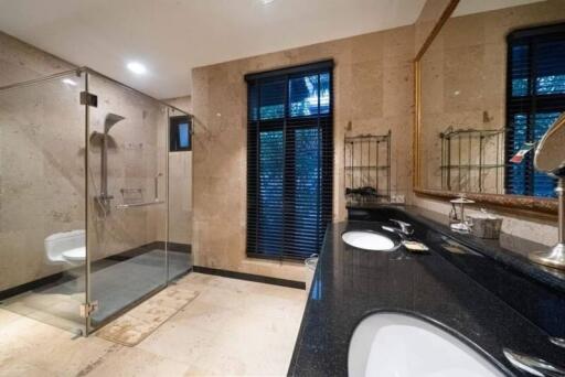 Modern bathroom with glass shower, double sinks, and marble flooring