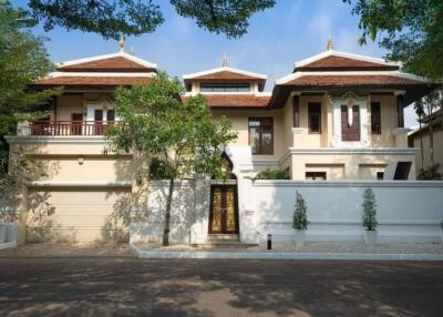 Front view of a large, luxurious house with trees and driveway