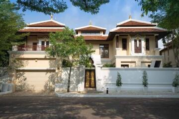 Front view of a large, luxurious house with trees and driveway