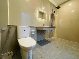 Modern bathroom with large tiles, mounted sink, mirror, and toilet