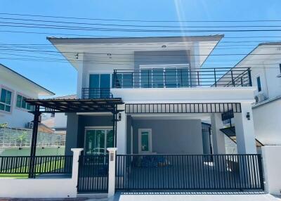 Exterior view of a modern two-story house with a gated driveway and balcony