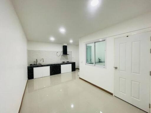 Clean modern kitchen with white walls, ceiling lights, and tiled floor