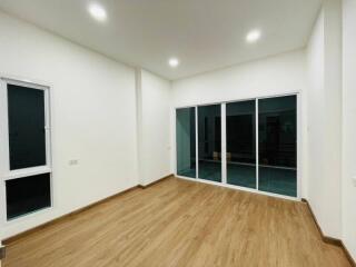 Well-lit main living area with wooden flooring and large glass doors