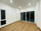 Well-lit main living area with wooden flooring and large glass doors