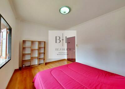 Spacious bedroom with natural light and red bedding