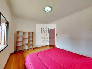 Spacious bedroom with natural light and red bedding