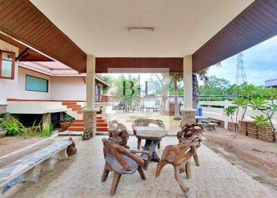 Covered outdoor seating area with unique wooden furniture and tiled flooring