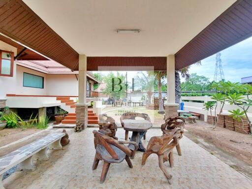 Covered outdoor seating area with unique wooden furniture and tiled flooring